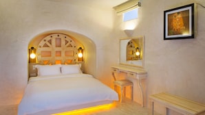 Een slaapkamer met een groot bed, een houten hoofdbord, een nachtkastje met een lamp, een spiegel en een inlijsting schilderij aan de muur.