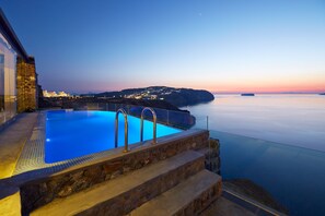 Een buitenzwembad, een infinitypool en ligstoelen