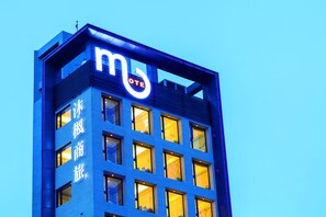 Un edificio moderno con un llamativo letrero que dice 'MOTEL', múltiples ventanas y fachada azul.