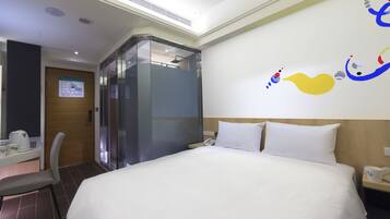 Una habitació d'hotel amb un llit gran, una taula de treball amb una cadira, un telèfon i una paret amb un mural colorit.