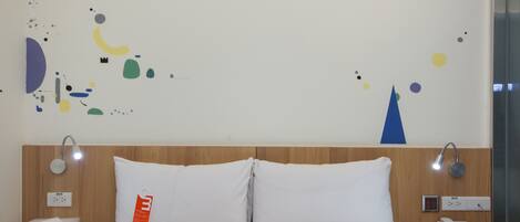 A hotel room with a bed, a nightstand, a phone, and a wall with abstract art.