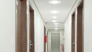 A clean, well-lit hallway with wooden doors and a tiled floor, leading to an elevator. - Imperial Plaza Hotel (Samambaia)