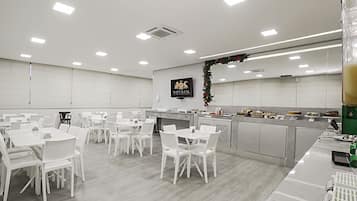 Un hall d’hôtel spacieux et moderne, avec des meubles blancs et un comptoir central.