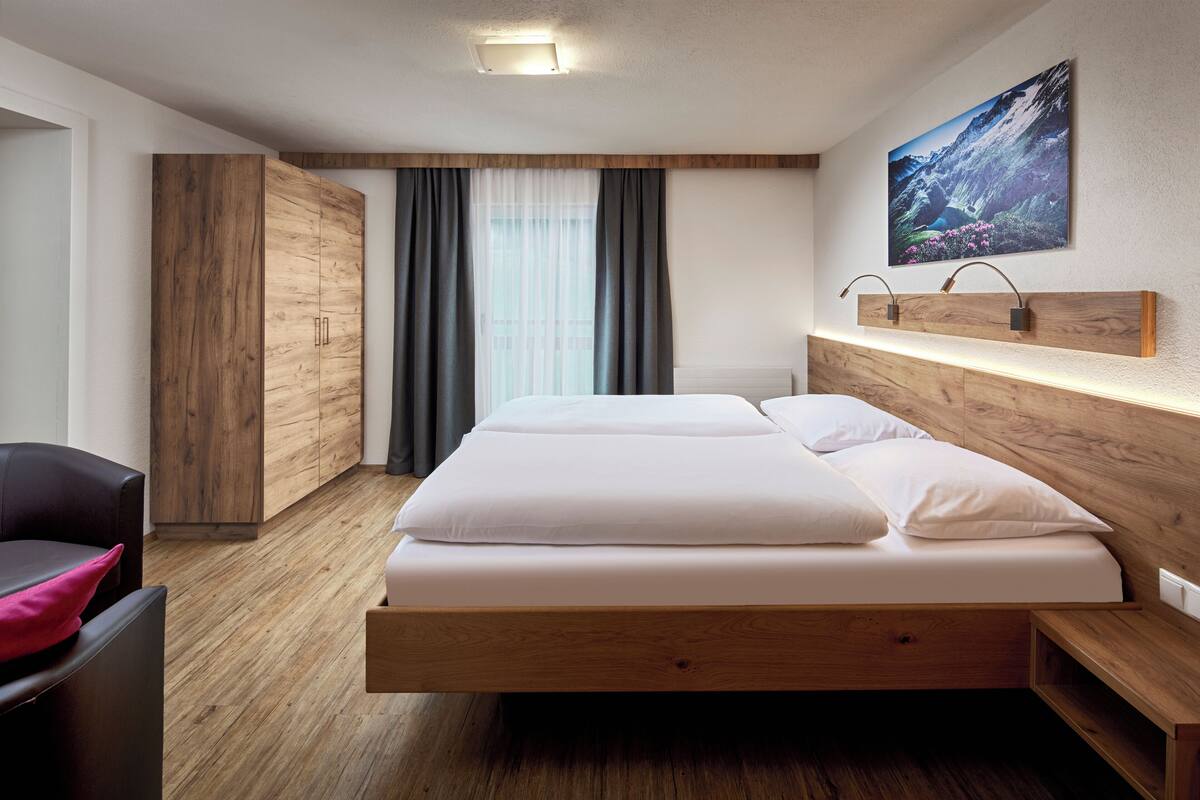 A modern hotel room with a wooden bed frame, a desk, and a chair.