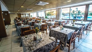 Un restaurant spacieux, doté de nombreuses tables et chaises, de grandes fenêtres donnant sur l’extérieur et d’un bar situé au fond de la salle.