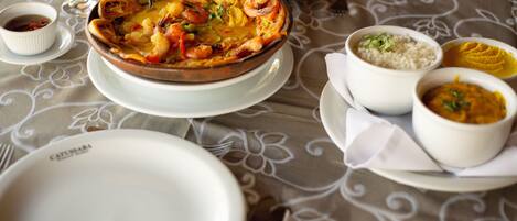 Una mesa de comedor con un plato de mariscos, arroz y diferentes acompañamientos.