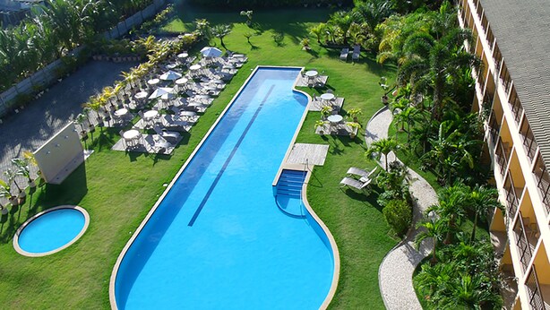 Une piscine de forme longue et étroite, entourée d’une pelouse bien entretenue, de plusieurs chaises longues et de parasols.