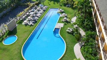 Alberca al aire libre, sombrillas en la alberca y camastros