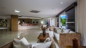 Un hall d’entrée spacieux avec un comptoir d’accueil, plusieurs drapeaux, des coins salon confortables et une grande fenêtre donnant sur l’extérieur.