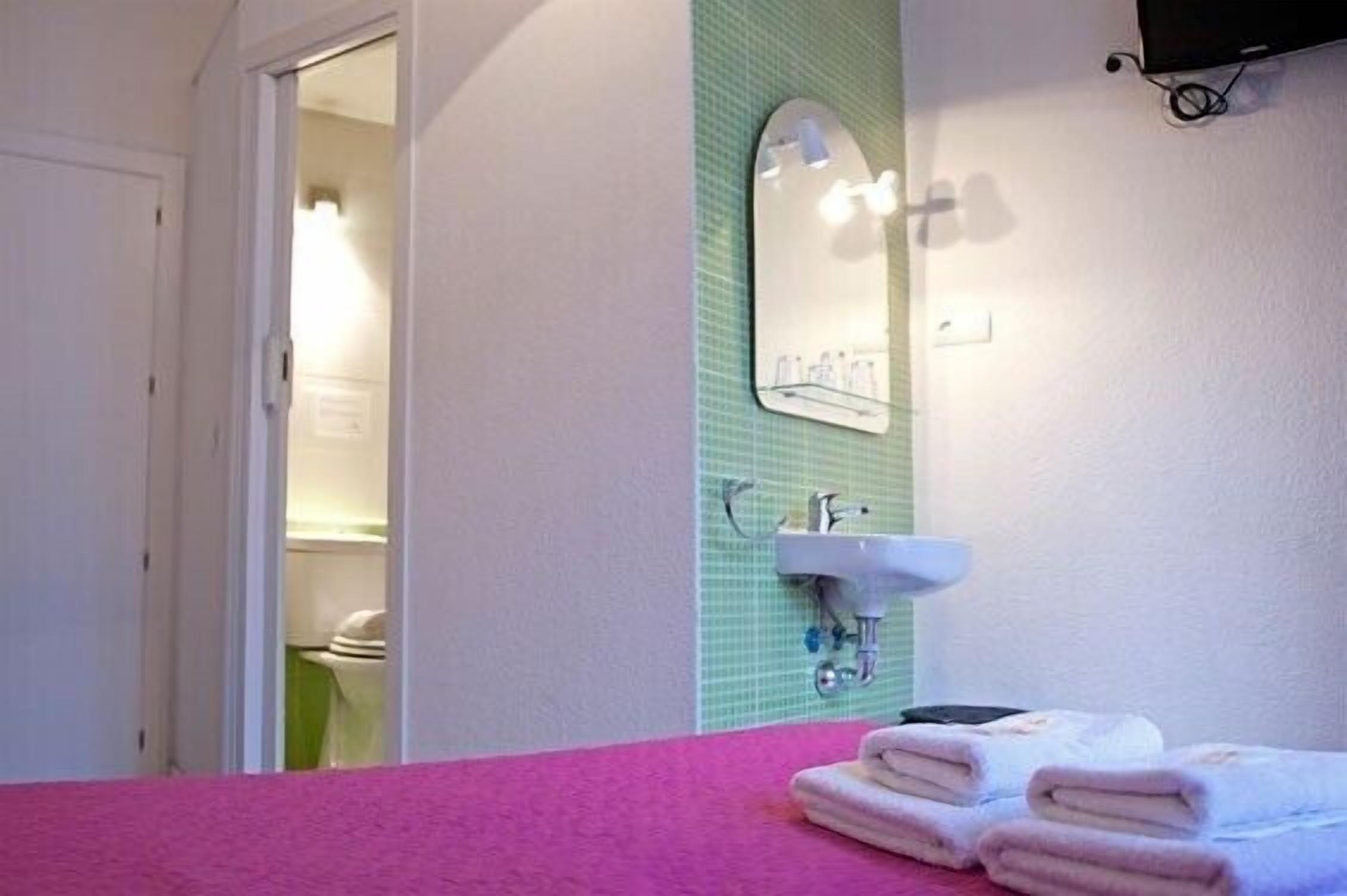 A bathroom with a pink towel rack, a sink, and a mirror.