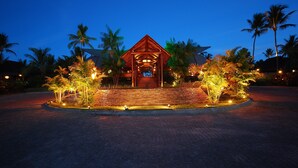 A wooden structure with a roof, surrounded by palm trees and illuminated by lights. - NANNAI Muro Alto (Ipojuca)