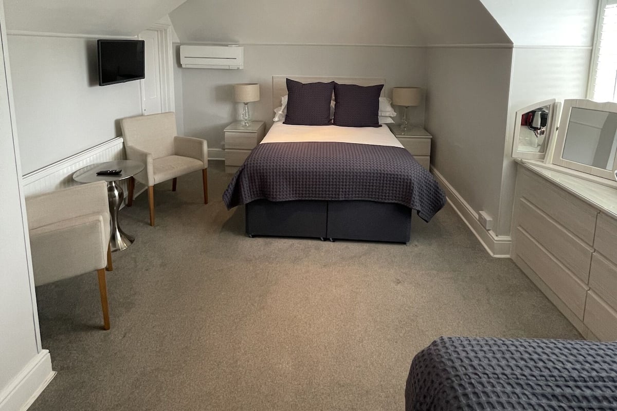 A bedroom with a bed, bedside tables, a TV, and a desk with a chair.