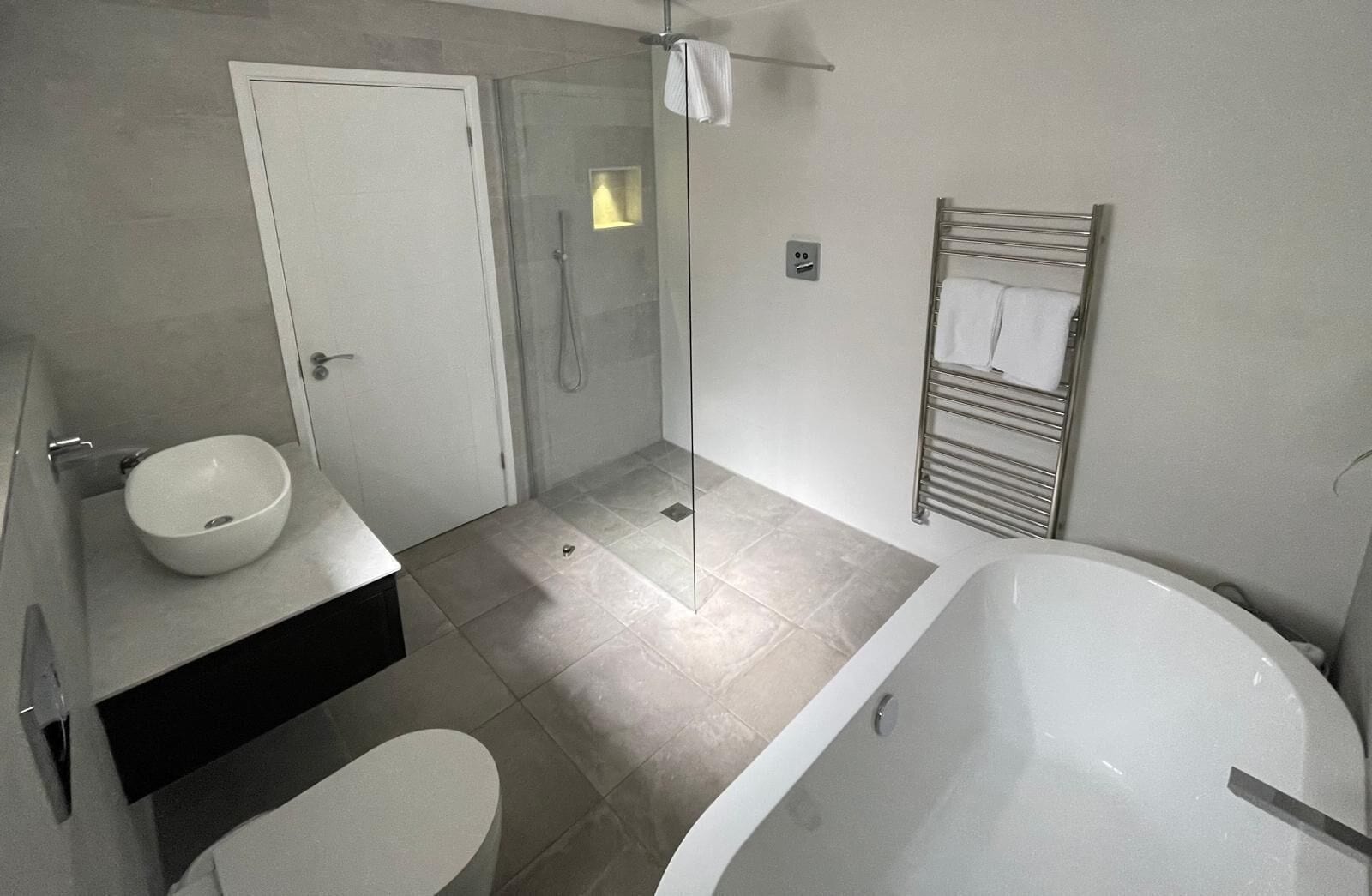 A modern bathroom with a bathtub, a sink, and a shower area.