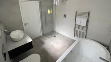 Ein modernes Badezimmer mit Badewanne, Waschbecken und Duschbereich.