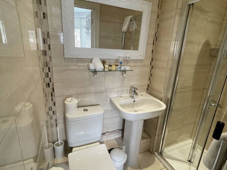 Une salle de bain moderne équipée de toilettes, d’un bidet, d’un lavabo et d’une douche à parois de verre.