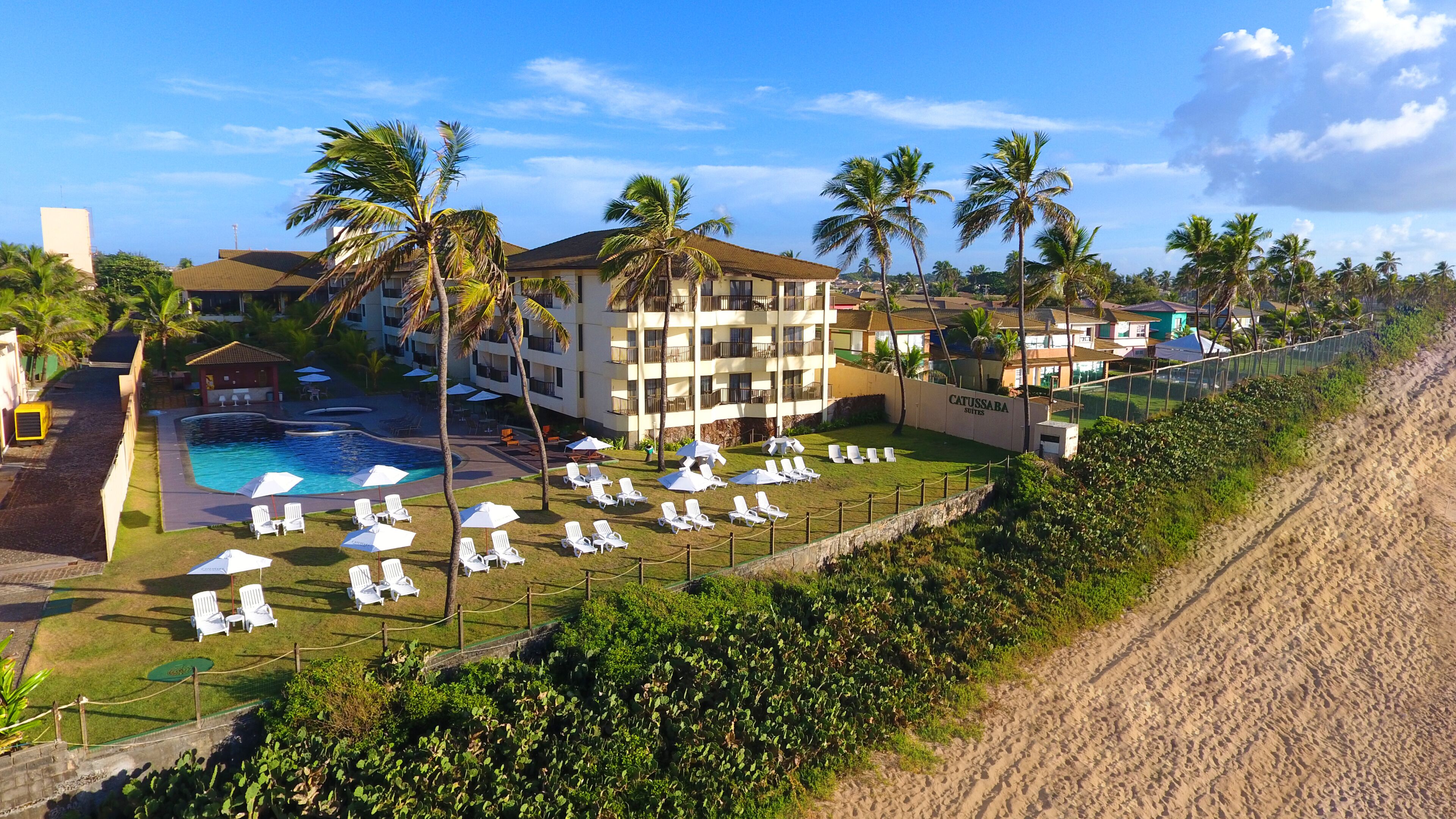 A resort with a swimming pool, sun loungers, and palm trees.