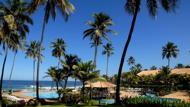 A resort with a pool, palm trees, and a beach view. - Catussaba Suítes Resort (Salvador)