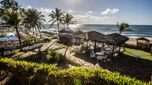 A beachside resort with outdoor seating, palm trees, and a view of the ocean. - Catussaba Suítes Resort (Salvador)