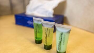 Three tubes of shampoo and conditioner on a table with a tissue box in the background.