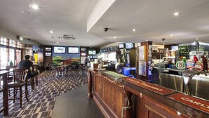 A bar area with a counter, seating, and various screens displaying content. - Boomerang Hotel (Lavington)