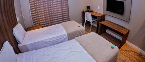 Une chambre d’hôtel avec deux lits, un bureau, une chaise, une télévision et une fenêtre avec des rideaux.