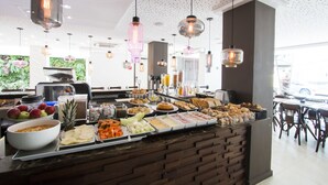 A buffet with various food items and a seating area with tables and chairs. - The Hotel (Salvador)