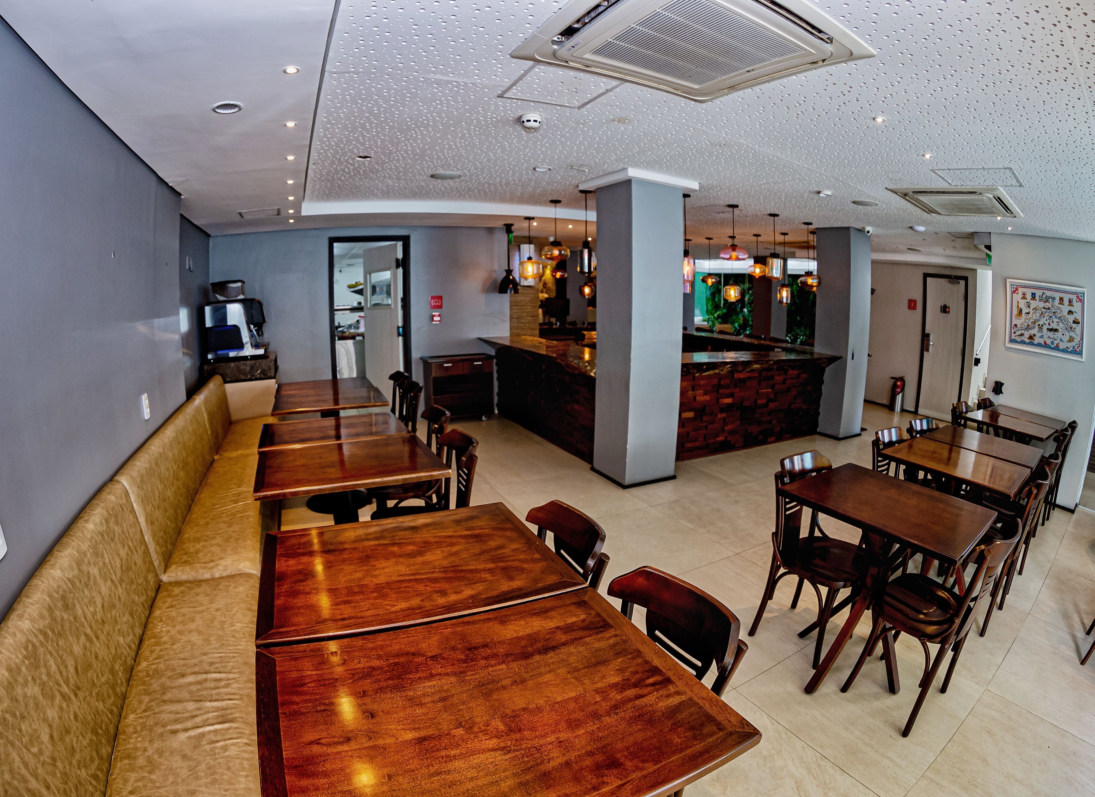 A restaurant with wooden tables and benches, a bar area, and a kitchen visible through an open door.