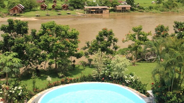 A pool with a checkmark symbol, surrounded by lush greenery and a mountainous landscape in the background. - Vansana Vang Vieng (Vang Vieng)