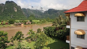 A riverside view with a house, a river, and mountains in the background. - Vansana Vang Vieng (Vang Vieng)