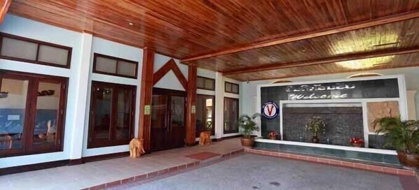 A hotel entrance with a wooden ceiling, large windows, and a welcome sign.