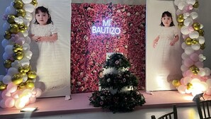 A decorated stage with a neon sign reading "MI BAPTIZO" and a floral backdrop.
