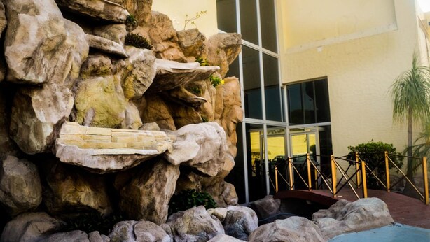 A rock formation with a small waterfall and a glass entrance to a building.