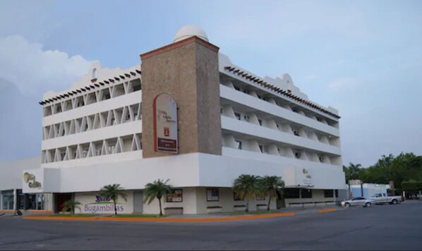 A multi-story building with a central tower, multiple balconies, and a sign for 'Bugambillas'.