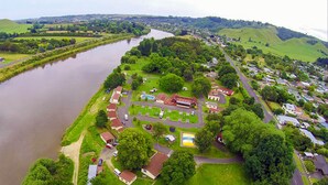 An aerial view of a riverside village with houses, a swimming pool, and a small park. - Whanganui River Top 10 Holiday Park (Whanganui)