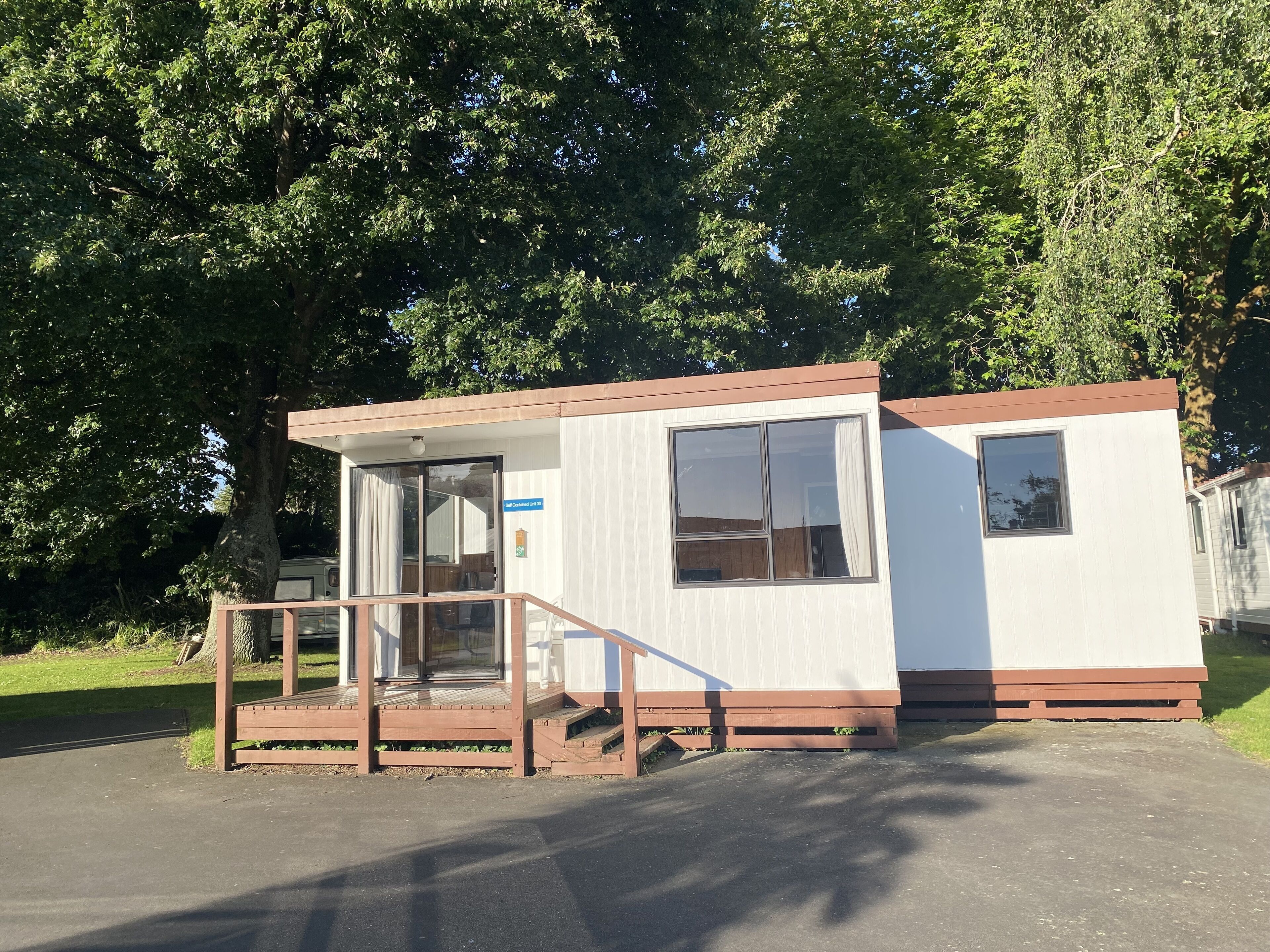 Une petite maison mobile d’un seul étage, dotée d’un porche et d’une porte coulissante.