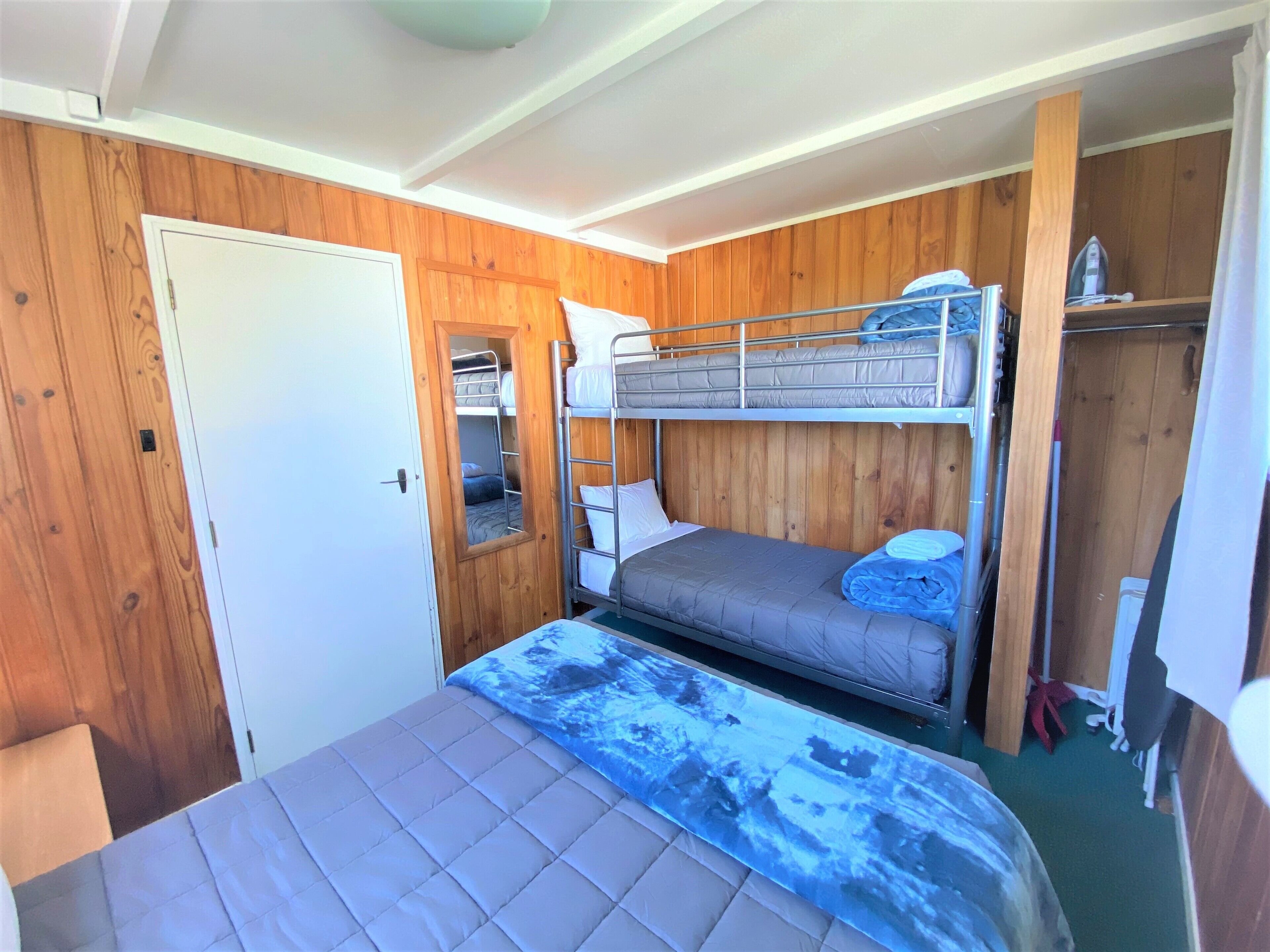 Une chambre avec un lit superposé, des murs en bois, une porte et un miroir.