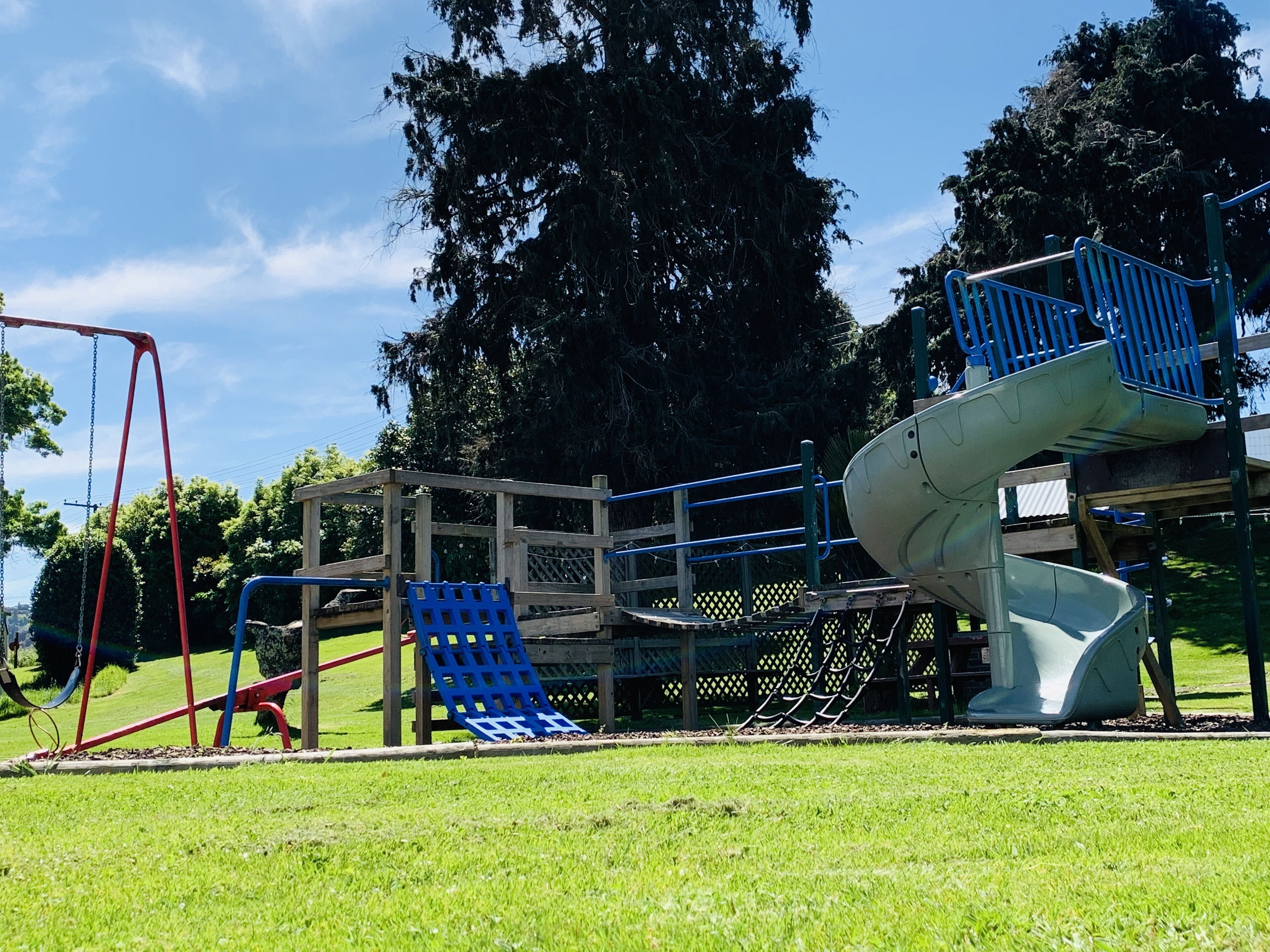 Une aire de jeux avec un toboggan et des balançoires.
