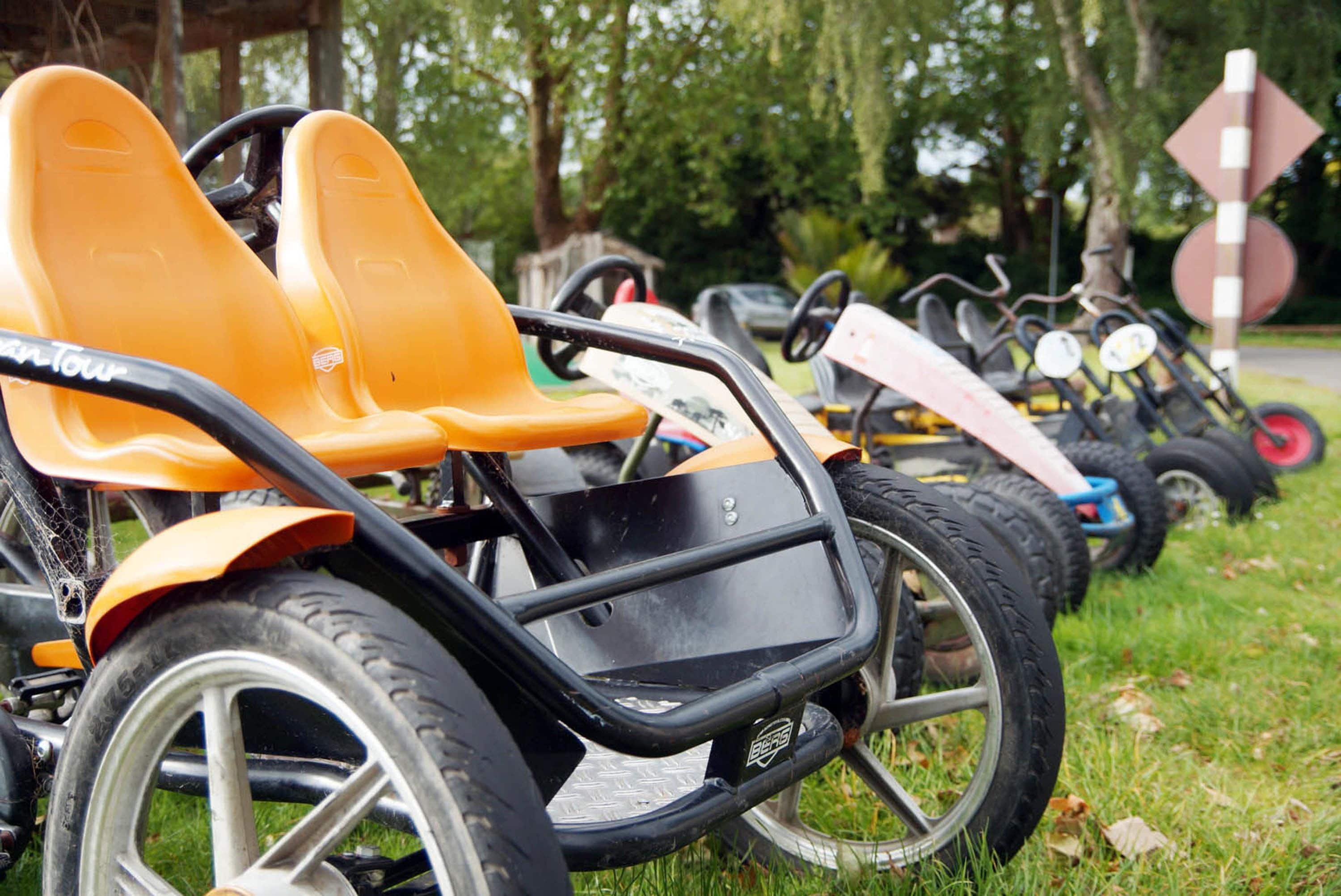 En række stillestående gokarts på græs.