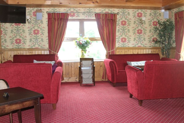 Una habitación con dos sofás rojos, una mesa de madera y una ventana con cortinas.