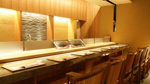 Una cocina moderna con armarios de madera, una encimera amplia y varios taburetes de bar.