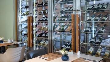 Un restaurante con una estantería llena de botellas de vino, una mesa con un florero y una silla.
