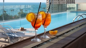 Un bar junto a la piscina con dos cócteles, una rodaja de naranja y vistas a la piscina.