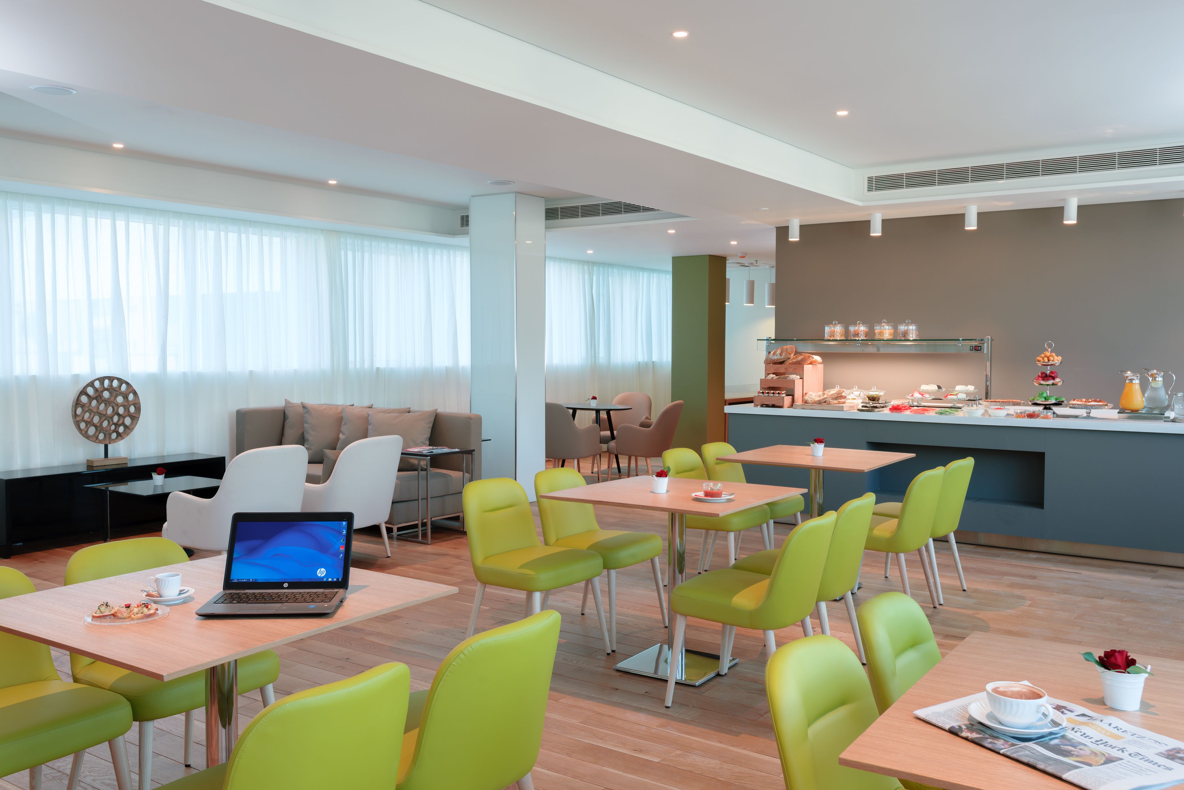 A modern hotel lobby with a seating area, a bar, and a dining space.