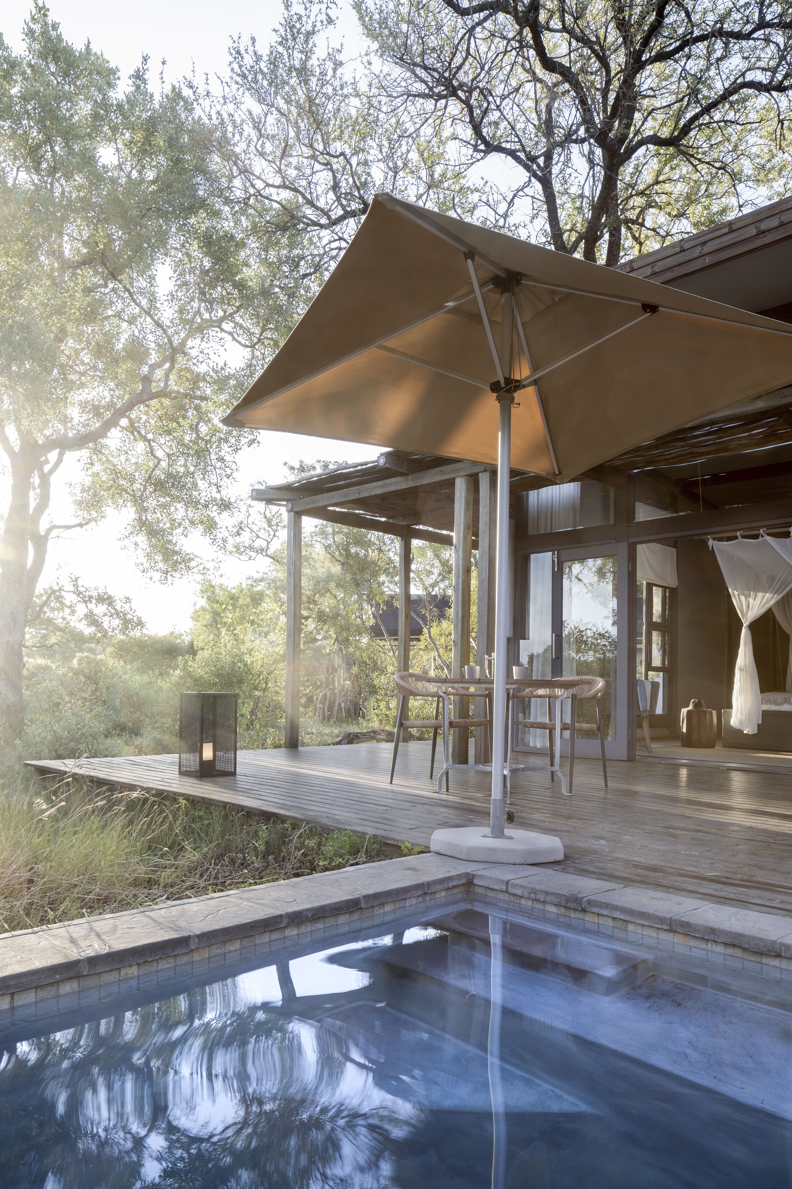 A pool area with a pergola, outdoor furniture, and a view of trees.