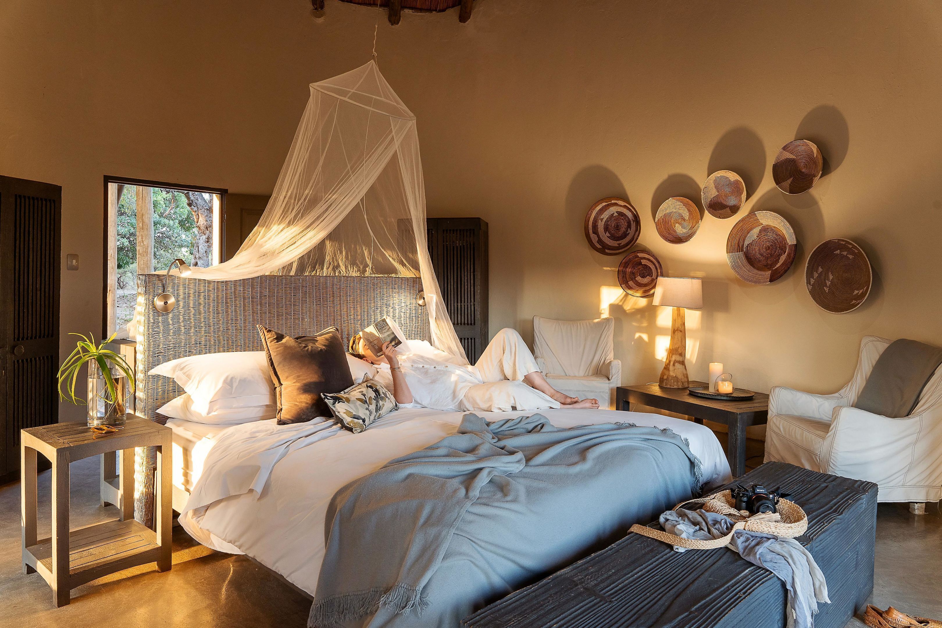 Ein Schlafzimmer mit einem Bett, Nachttischen, einem Sessel, einer Nachttischlampe und einer Wand mit dekorativen Tellern.