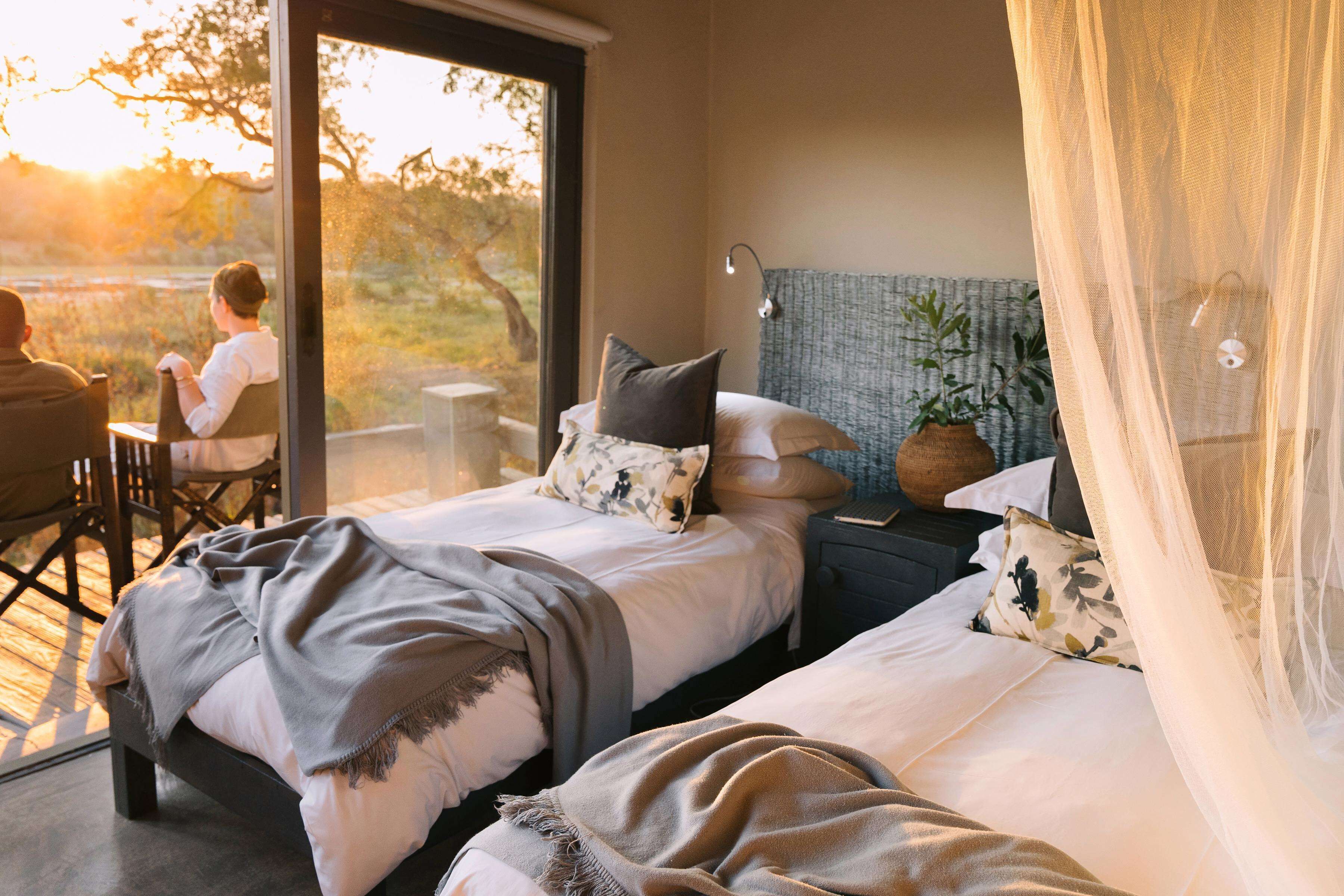 A bedroom with two beds, a large window, and a view of the outdoors.