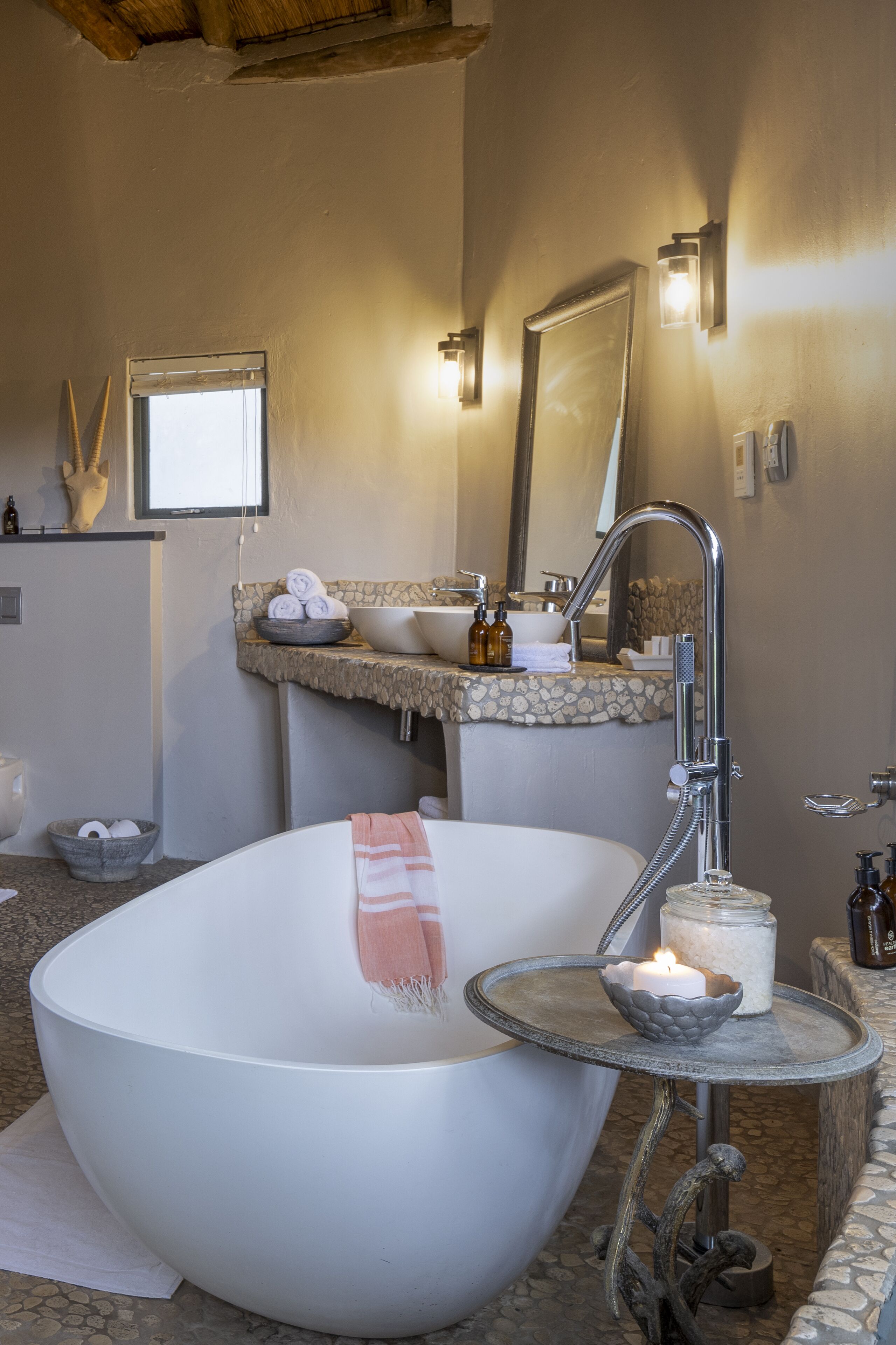 A modern bathroom with a freestanding bathtub, a vanity with a stone countertop, and a mirror above the sink.