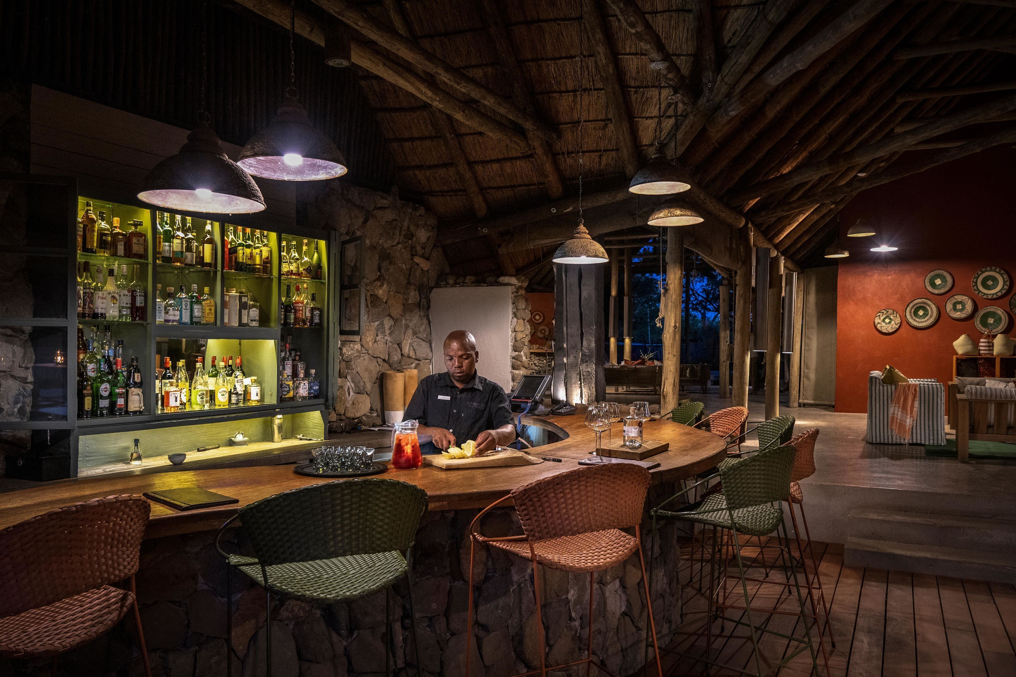 Eine Bar mit einer Steinwand, Holzbalkendecke und hängenden Pendelleuchten.