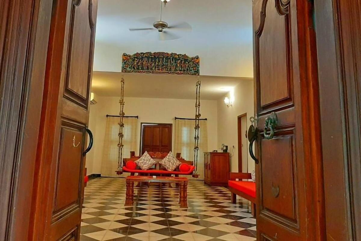 Une pièce avec un sol à carreaux, un canapé rouge, un lustre et un ventilateur de plafond.