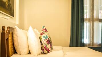 Una cama bien hecha con ropa de cama blanca y una almohada con motivos florales.